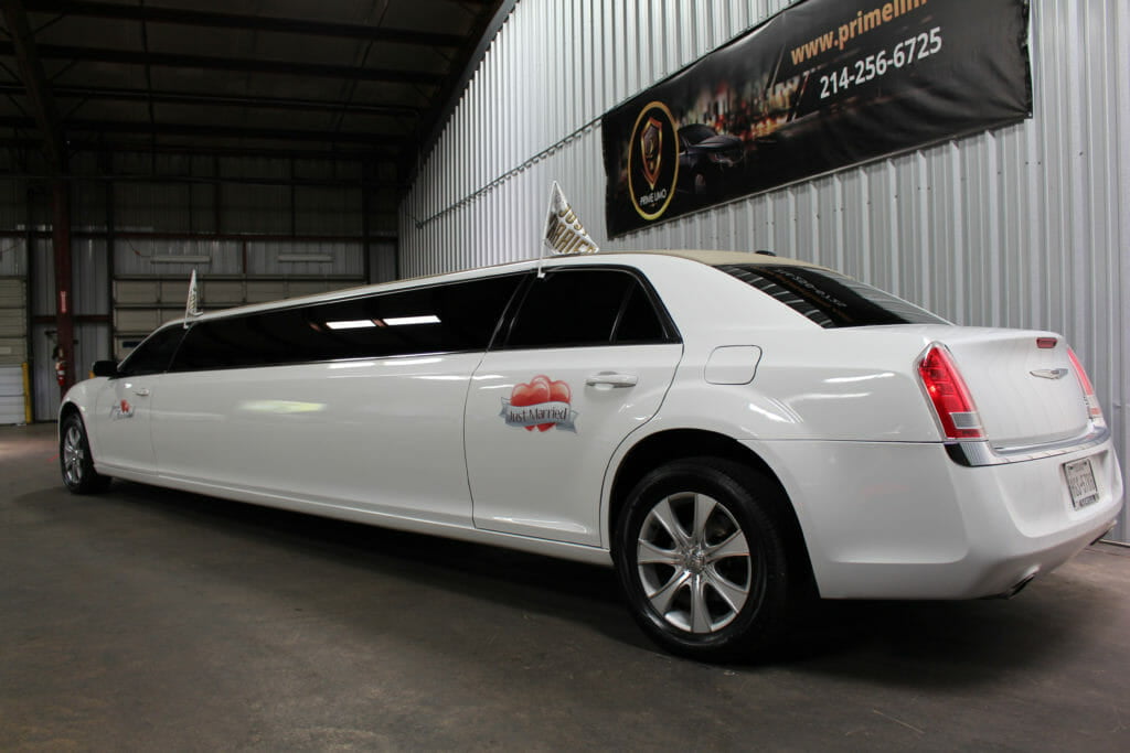 White Chrysler 300 limo with Just Married Signs and flags